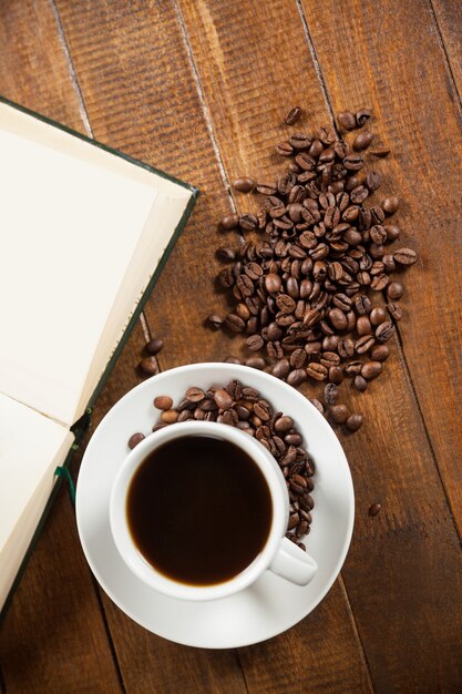 Tazza di caffè con chicchi di caffè e libro