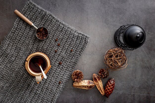 Tazza di caffè con chicchi di caffè su una sciarpa a maglia grigia