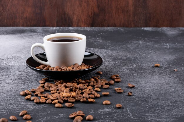 Tazza di caffè con chicchi di caffè sul tavolo scuro