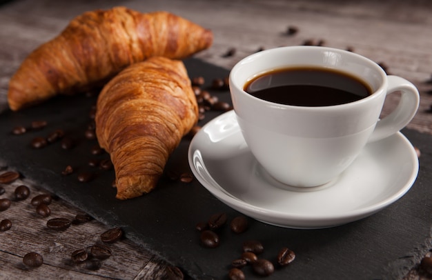 Tazza di caffè con deliziosa pasticceria e chicchi di caffè spalmati. Spuntino mattutino.