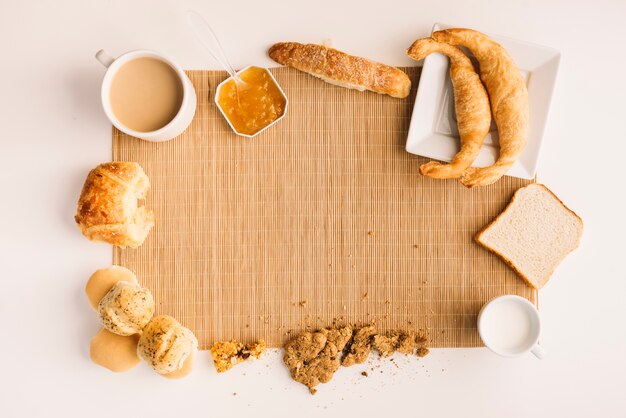 Tazza di caffè con diversi prodotti da forno e marmellata sul tavolo