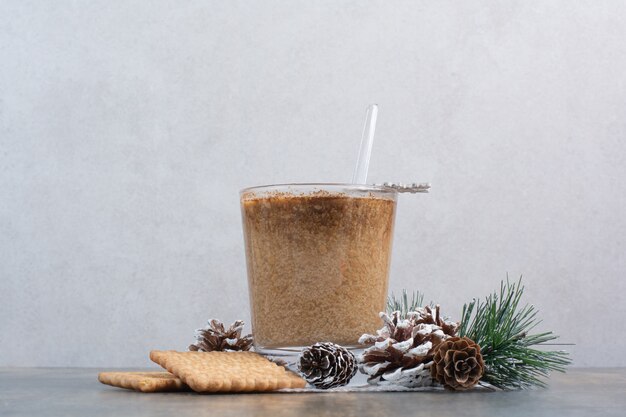 Tazza di caffè con gustosi cracker e pigne nelle quali su sfondo marmo. Foto di alta qualità