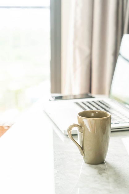 tazza di caffè con il computer portatile e la bella decorazione della tabella di lusso in salotto interno per lo sfondo