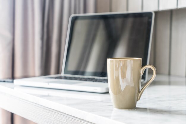 tazza di caffè con il computer portatile e la bella decorazione della tabella di lusso in salotto interno per lo sfondo
