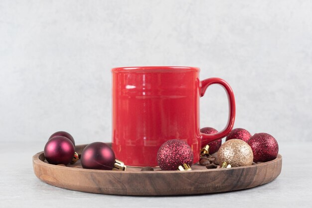 Tazza di caffè con ornamenti natalizi sul piatto di legno