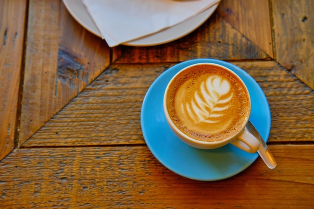 Tazza di caffè con una decorazione floreale bianca messa su una superficie di legno