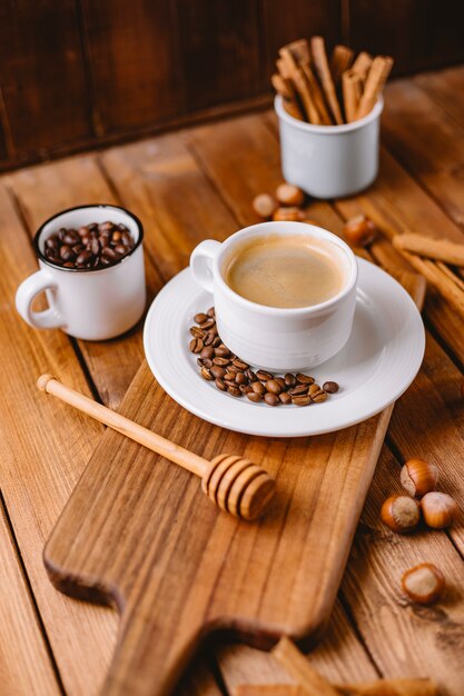 Tazza di caffè decorata con chicchi di caffè disposti sul verticale di bordo di servizio in legno