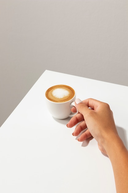Tazza di caffè della holding della mano ad alto angolo