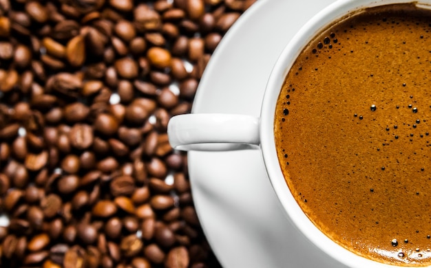 Tazza di caffè e chicchi di caffè sul tavolo, vista dall&#39;alto, caffè d&#39;amore, chicchi di caffè marrone isolato su sfondo bianco, tazza di caffè caldo con chicchi di caffè