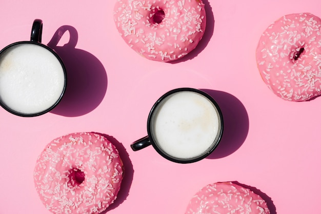 Tazza di caffè e ciambelle su sfondo rosa