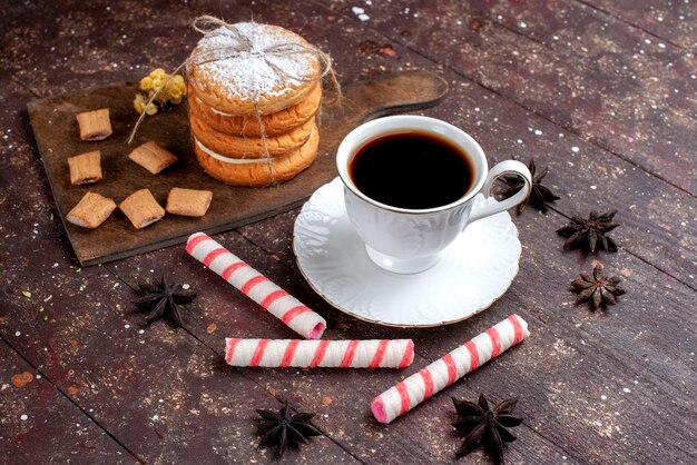 tazza di caffè forte e caldo insieme a biscotti e torta di biscotti sulla scrivania in legno marrone, torta di biscotti da forno di frutta dolce