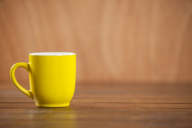 tazza di caffè giallo su tavola di legno