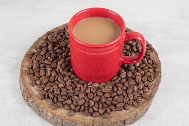 Tazza di caffè rossa con chicchi di caffè sul pezzo di legno