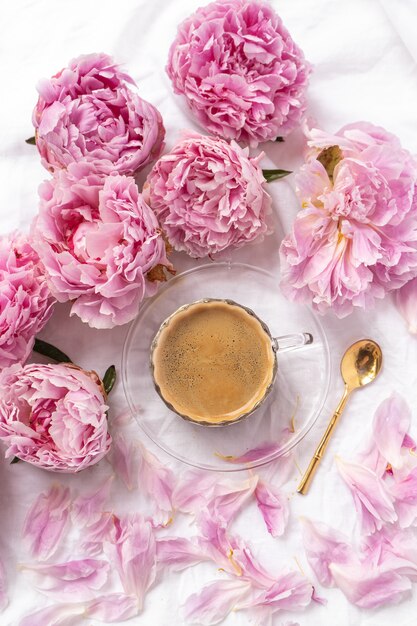 tazza di caffè solubile sul tavolo con peonie rosa sotto le luci