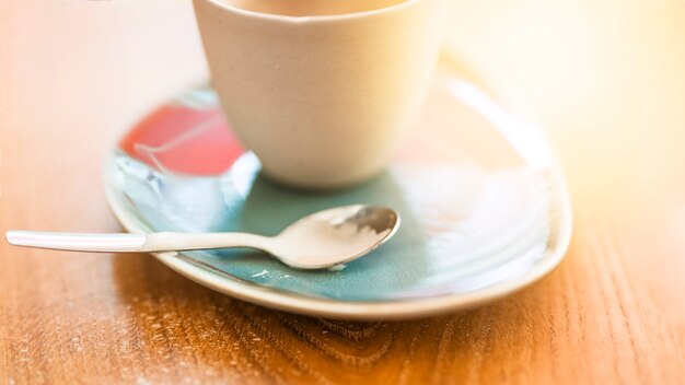 Tazza di caffè sul piattino con il cucchiaio sopra il contesto strutturato in legno