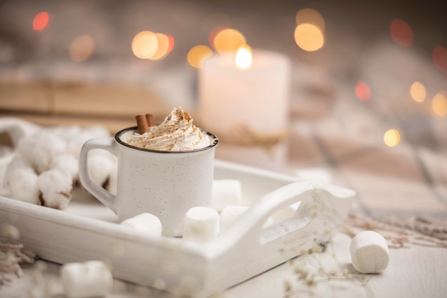 Tazza di caffè sul vassoio con marshmallow e bastoncini di cannella