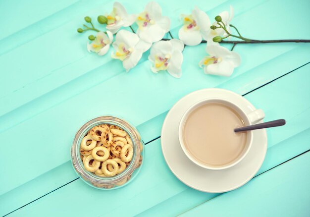 Tazza di caffè sul vecchio tavolo in legno vista dall'alto con fiori freschi primaverili con grande piatto di bubliks russi