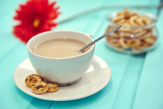 Tazza di caffè sul vecchio tavolo in legno vista dall'alto con fiori rossi freschi primaverili con grande piatto di bubliks russi