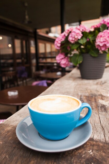 Tazza di caffè sulla vecchia tavola strutturata di legno nel caf` vuoto