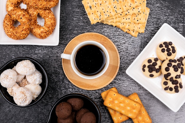 Tazza di caffè vista dall'alto con diversi biscotti sul tavolo scuro