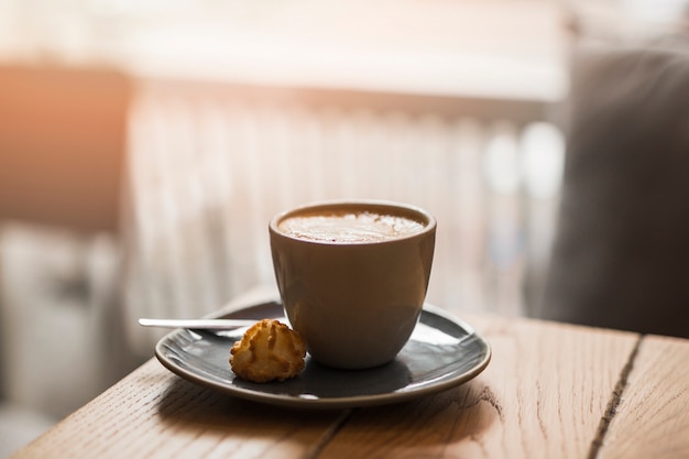 Tazza di latte con i biscotti sul piattino sopra il tavolo di legno