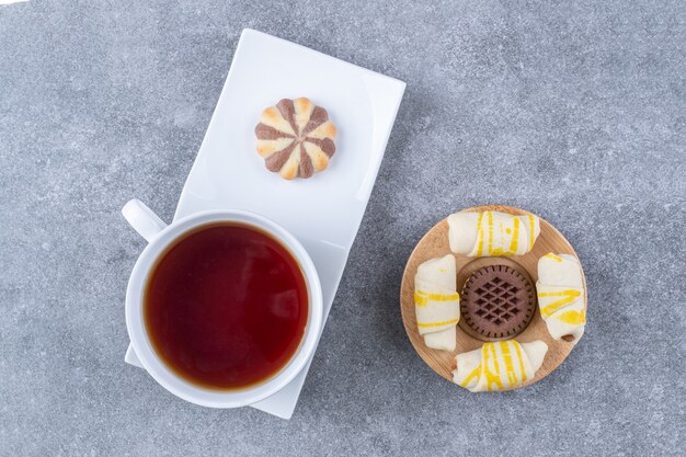 Tazza di tè aromatico con vari biscotti su superficie di marmo