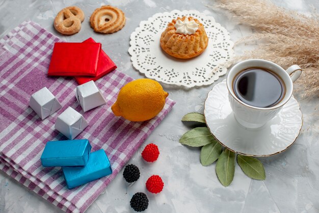 tazza di tè caldo all'interno della tazza bianca con cioccolatini al limone torta sulla luce, torta caramelle al cioccolato tè