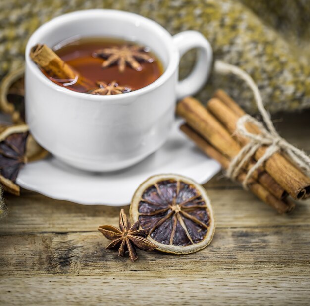 Tazza di tè caldo con bastoncini di cannella e deliziosi agrumi secchi