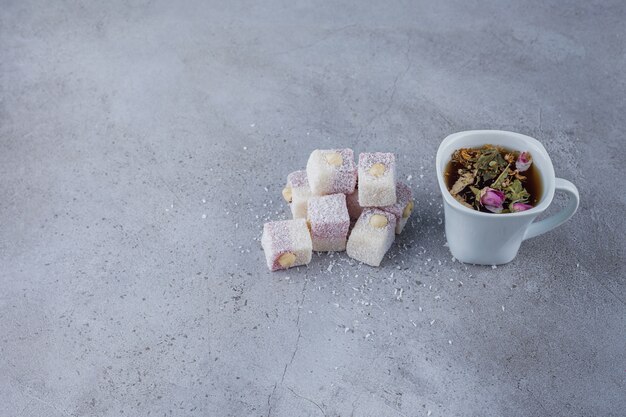 Tazza di tè caldo e dolci delizie con noci su sfondo di pietra.