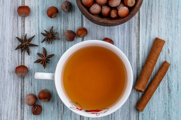 Tazza di tè con cannella e noci su uno sfondo grigio