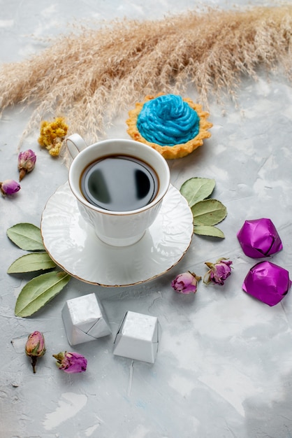 tazza di tè con caramelle al cioccolato torta di crema blu sulla scrivania bianco-grigio, cioccolato caramelle biscotto tè dolce