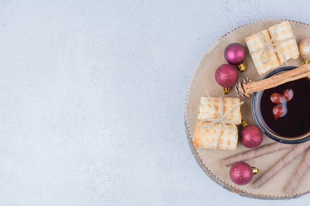 Tazza di tè con cinorrodi, biscotti e palline su tavola di legno.