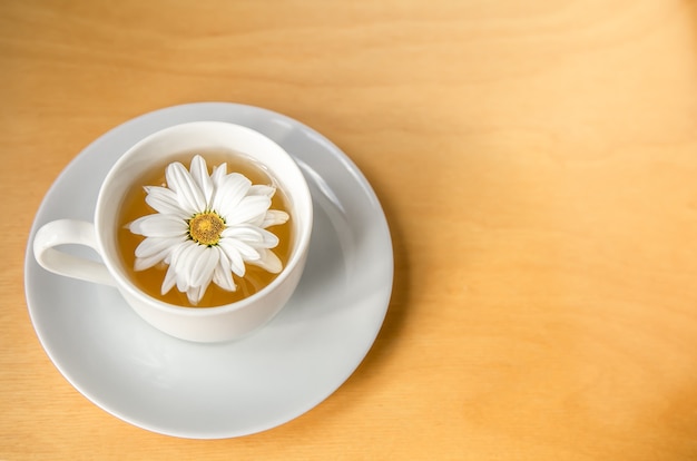 Tazza di tè con fiori di camomilla su uno spazio di copia di sfondo in legno