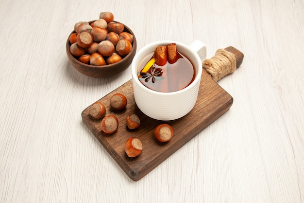 tazza di tè con nocciole fresche su bianco