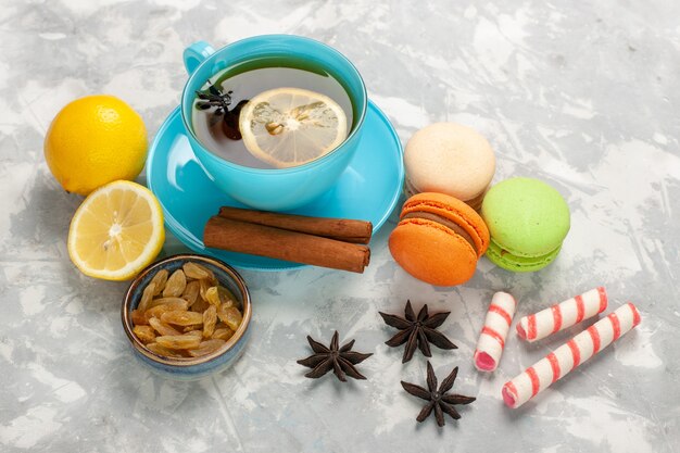 Tazza di tè con vista dall'alto a metà con macarons e uvetta sulla superficie bianca