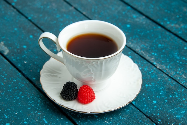 Tazza di tè di vista frontale con confitures sul biscotto rustico blu del biscotto dello zucchero del tè dello scrittorio