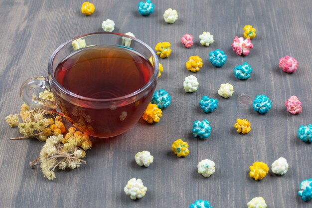 Tazza di tè, fiori secchi e popcorn colorati su una superficie di legno