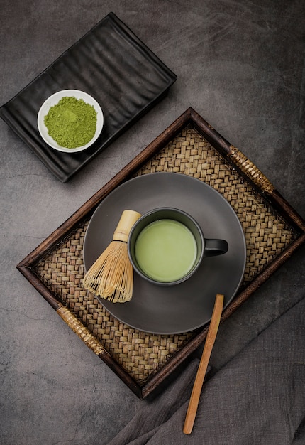 Tazza di tè matcha sul vassoio con frusta di bambù