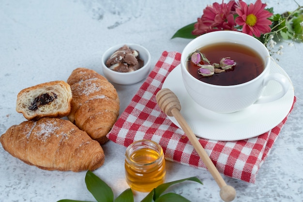 Tazza di tè nero caldo e croissant appena sfornati ripieni di cioccolato.