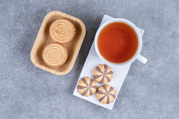 Tazza di tè nero con vari biscotti su superficie di marmok