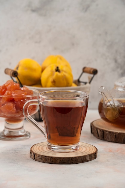 Tazza di tè nero, mele cotogne e marmellata sul tavolo di marmo.