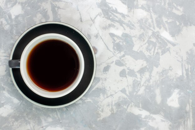 Tazza di tè vista dall'alto all'interno della tazza e del piatto sulla superficie bianca chiara