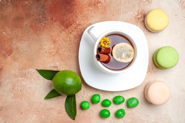 Tazza di tè vista dall'alto con caramelle e macarons su un biscotto al limone con tè da tavola marrone chiaro