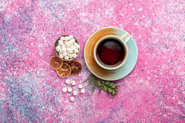 Tazza di tè vista dall'alto con confetture dolci bianche sulla superficie rosa