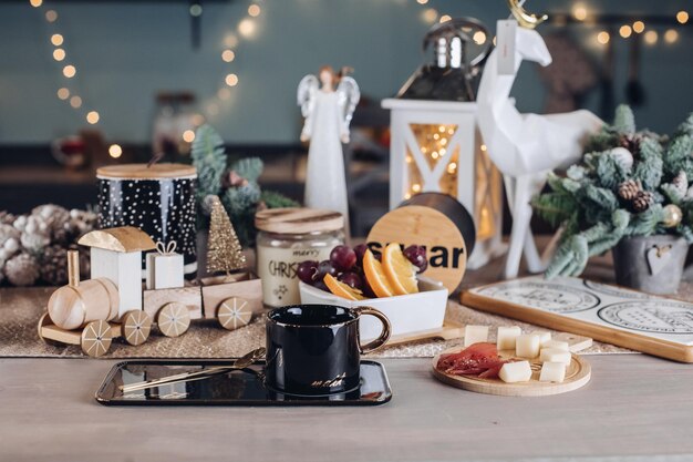 Tazza nera, cibo e decorazioni per il nuovo anno sono sul tavolo della stanza. Concetto di capodanno