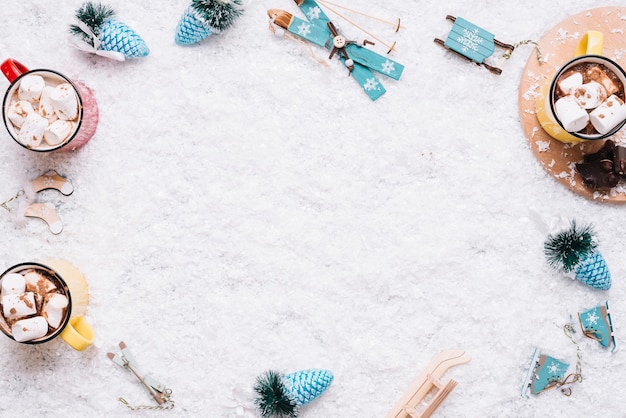 Tazze con marshmallow e giocattoli di Natale sulla neve
