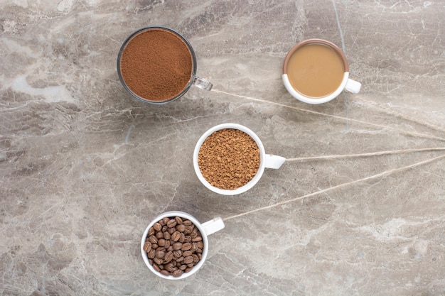 Tazze di caffè, chicchi di caffè e caffè macinato sulla superficie di marmo. Foto di alta qualità