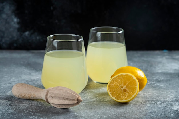 Tazze di limonata fresca con fetta di limone e alesatore in legno.