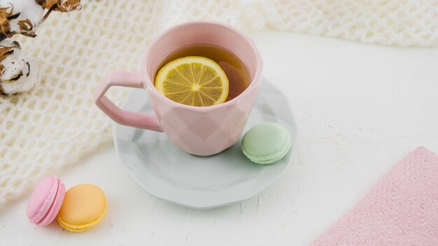 Tè al limone alle erbe con amaretti su sfondo bianco