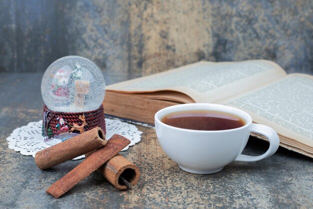 Tè aromatico in tazza bianca con cannella sul tavolo di marmo